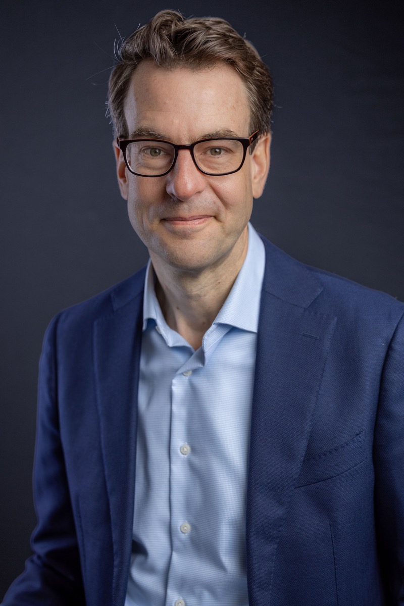 Zakelijk studio-portret man met bril in blauw colbert